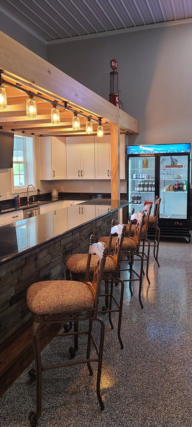 A kitchen with a bar and stools and a refrigerator.