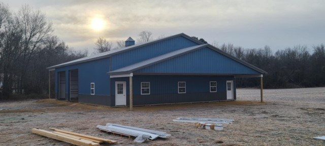 A blue building is being built in the middle of a field.