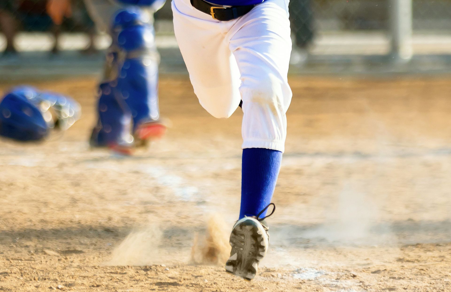 A baseball player is running towards home plate on a baseball field.