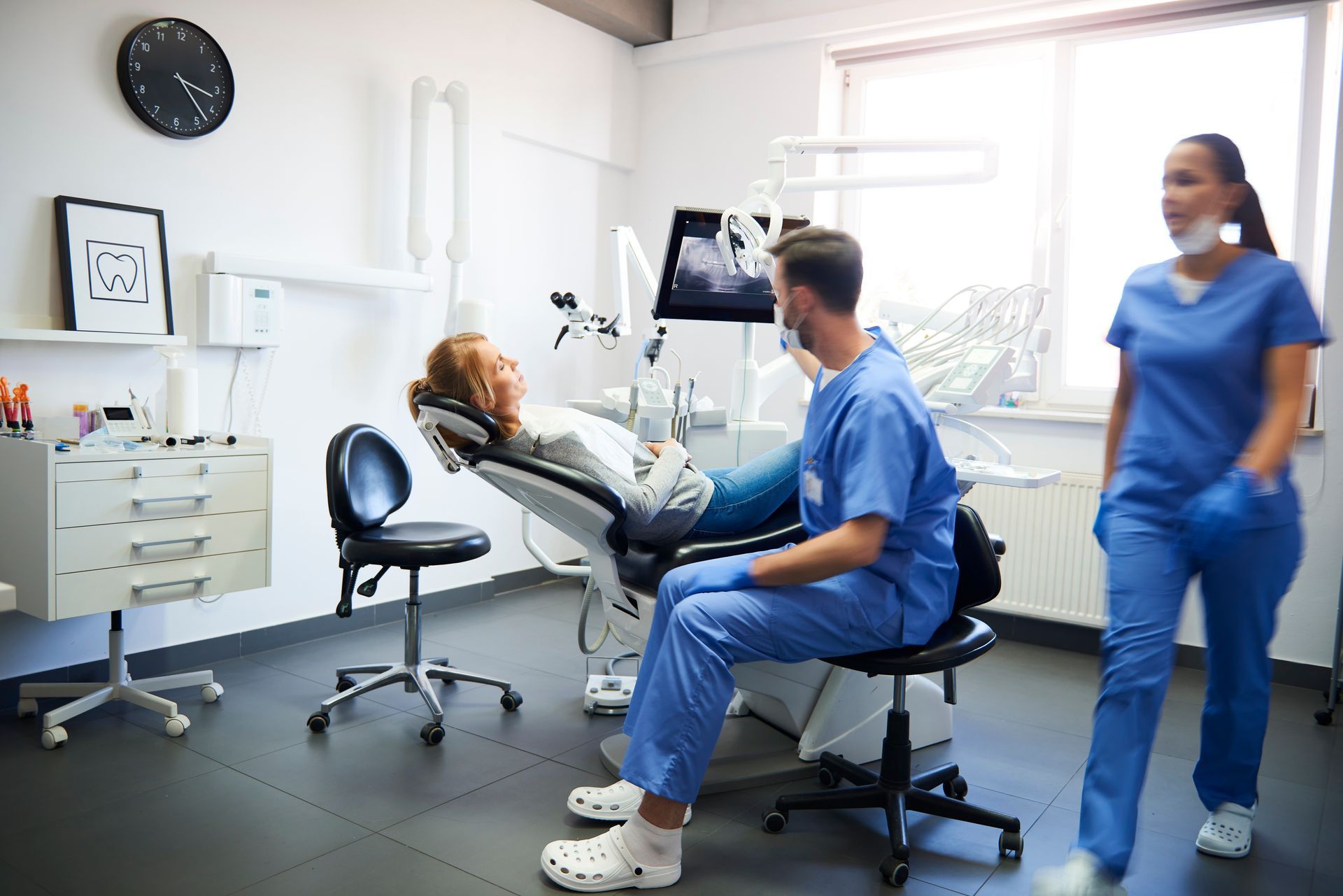 A blurred view of busy dentists at work at a clinic with a patient on a dental chair. A blurred view of busy dentists at work at a clinic with a patient on a dental chair.