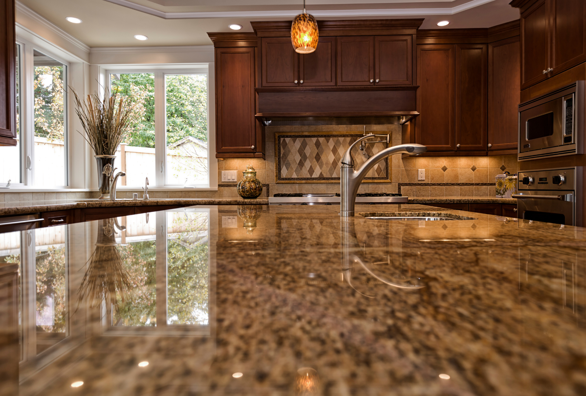 A kitchen with granite counter tops , wooden cabinets , stainless steel appliances and a sink.
