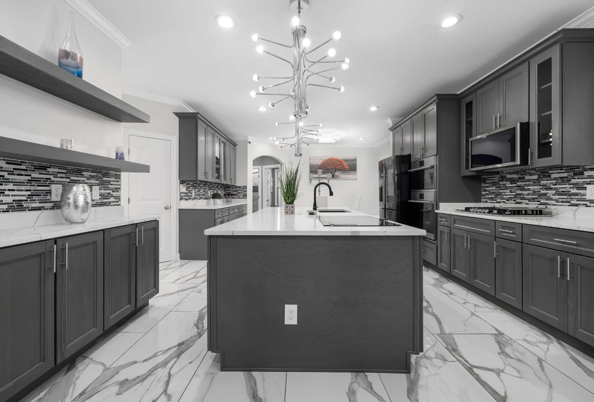 A kitchen with gray cabinets and white counter tops and a large island in the middle.
