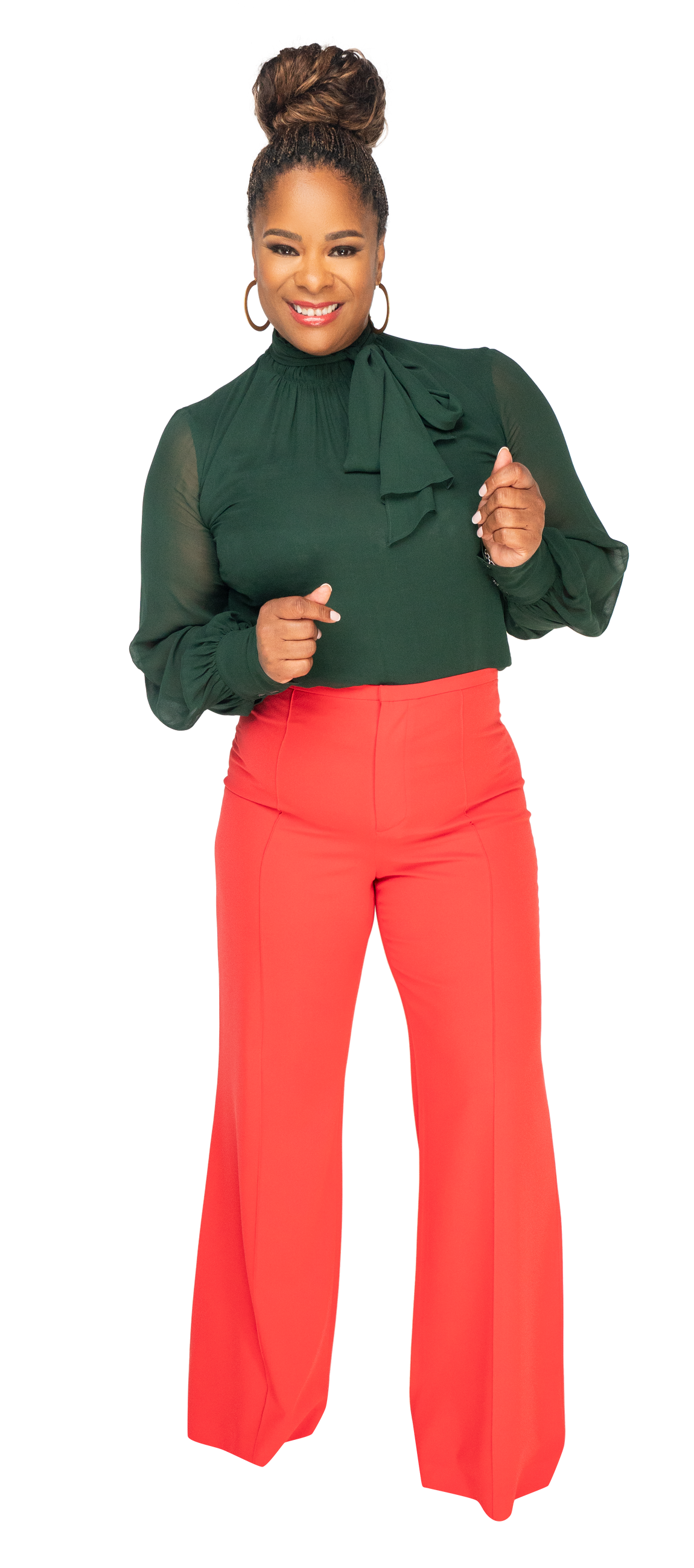 A woman wearing a green top and red pants is pointing at the camera.
