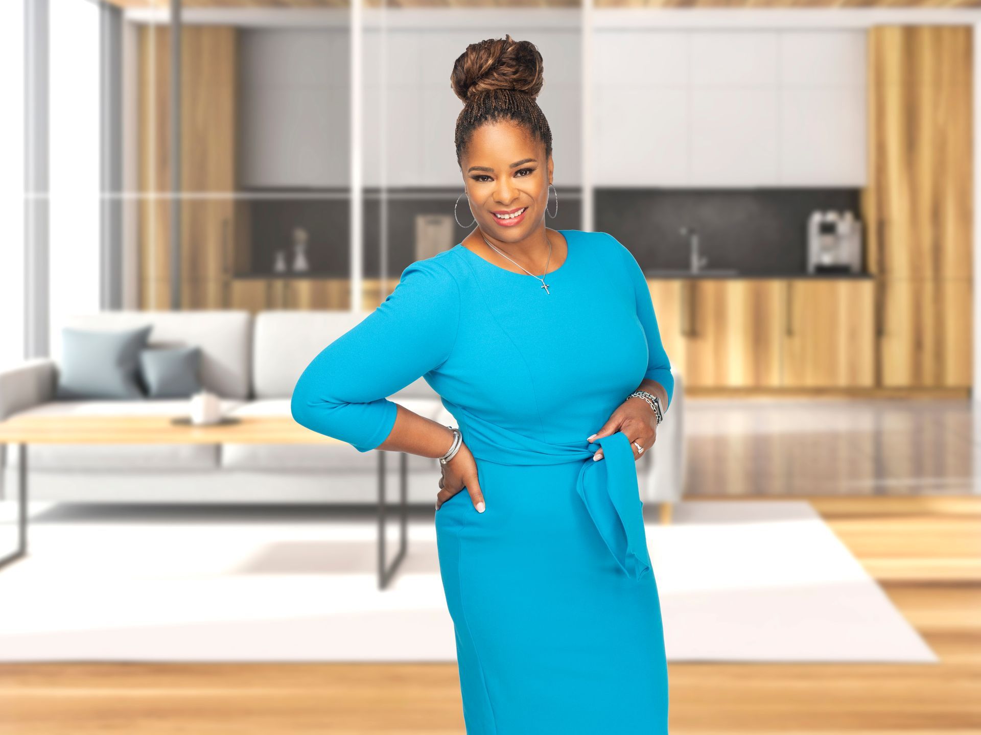 Coach Shermaine in a blue dress is standing in a living room.