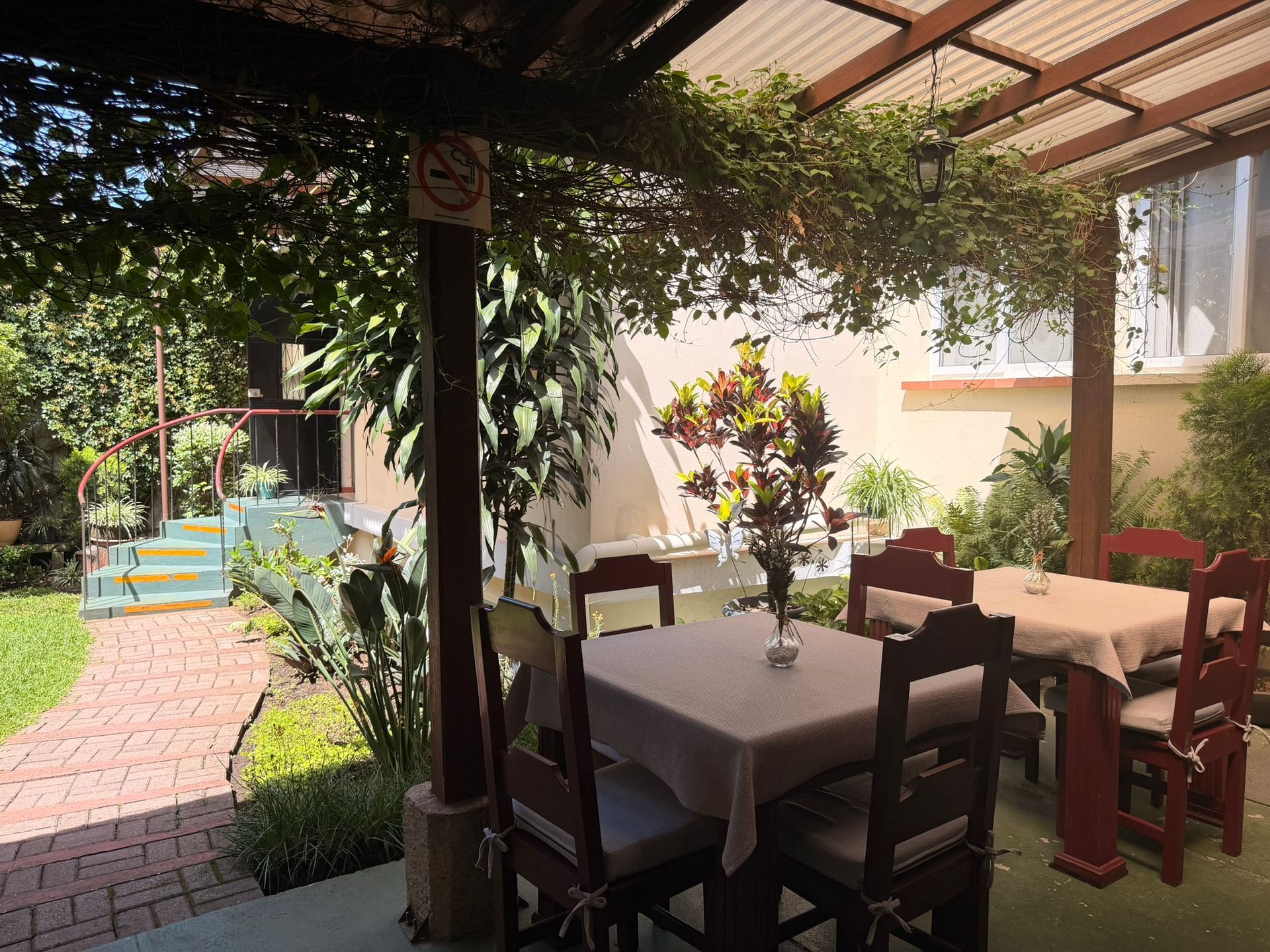 Acogedora mesa de comedor con mantel naranja, vajilla blanca y plantas verdes junto a la chimenea.