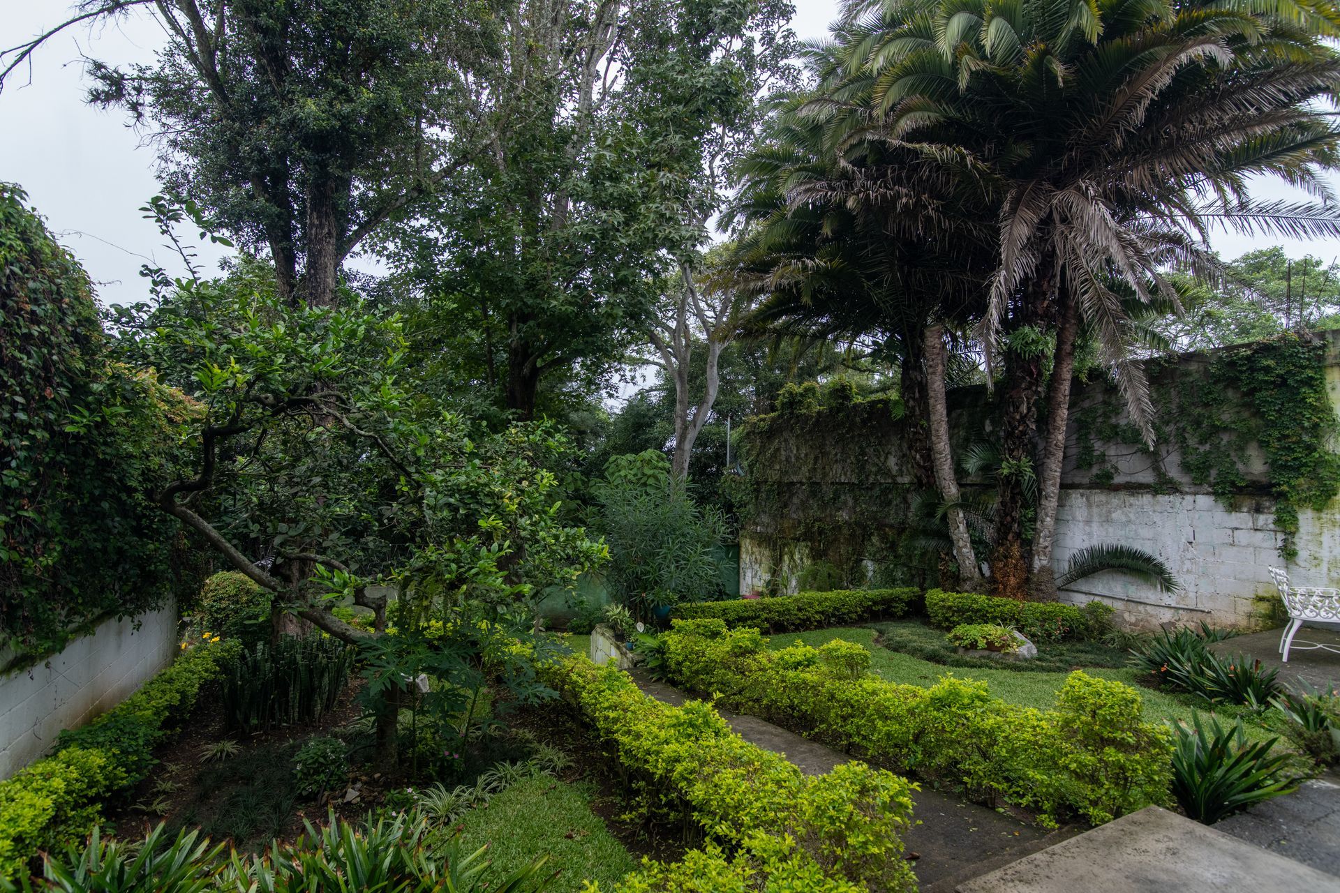 Acogedora habitación con dos camas, puertas correderas de cristal, escritorio y silla con vistas a un jardín.