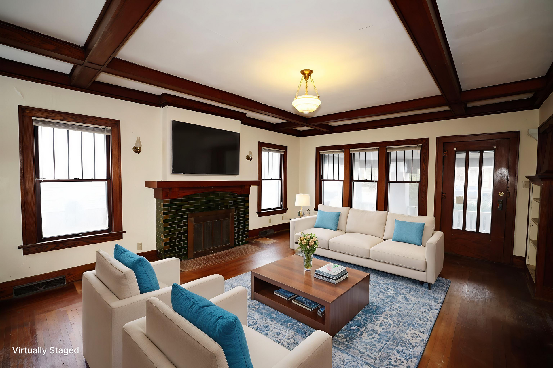 Bright living room with fireplace, sofas, coffee table, wall-mounted TV, and dark wood trim.