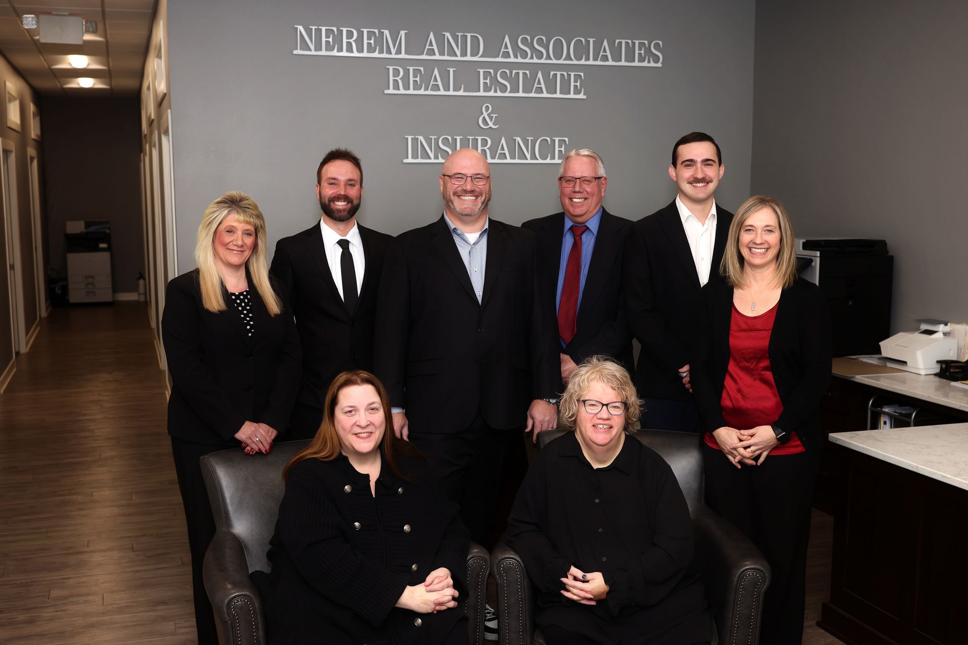 Seven people pose in a law office lobby with an insurance sign on the wall.