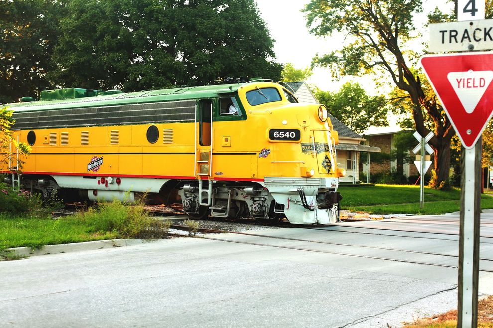 Yellow Union Pacific train crossing a street beside a red stop sign on a sunny day