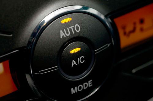A close up of an auto and a/c mode button on a car dashboard.