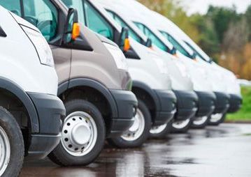 A row of vans parked next to each other in a parking lot.