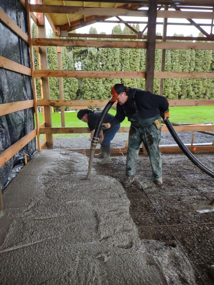 Two men are working on a concrete floor in a building.