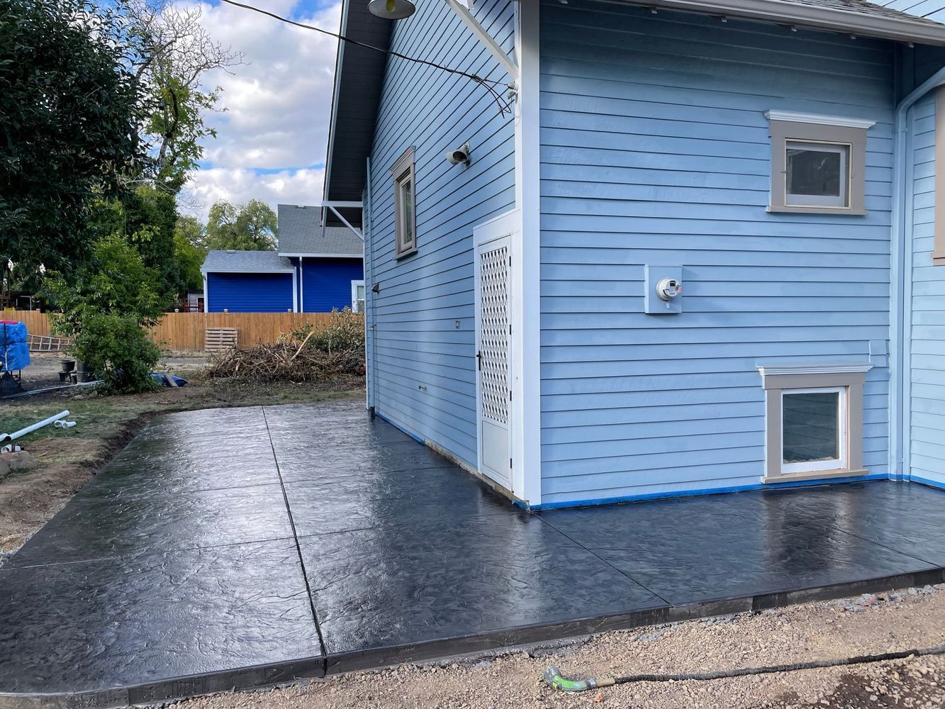 A blue house with a concrete driveway in front of it.
