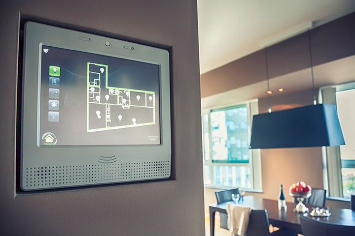 Modern smart home automation panel mounted on wall displaying interactive floor plan for efficient home management, with stylish dining room background.