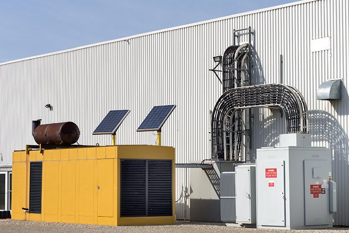 Industrial backup power generator with solar panels and ventilation system outside a commercial building, showcasing renewable energy integration and emergency preparedness.