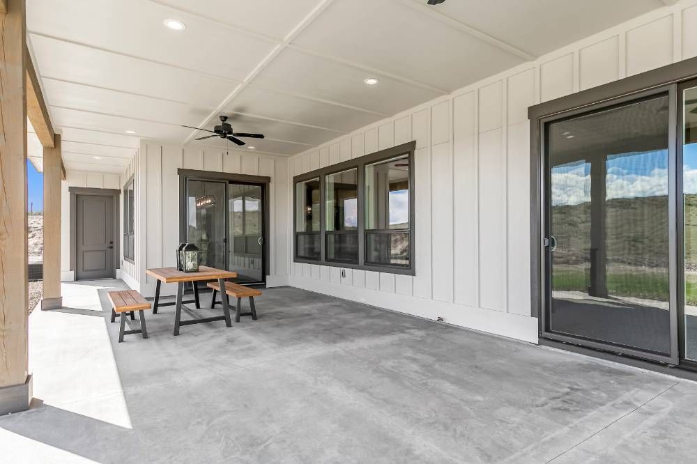 A large patio with a table and benches and a ceiling fan.