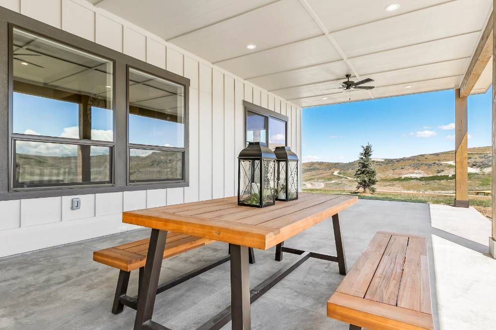 There is a picnic table and benches on the porch of a house.