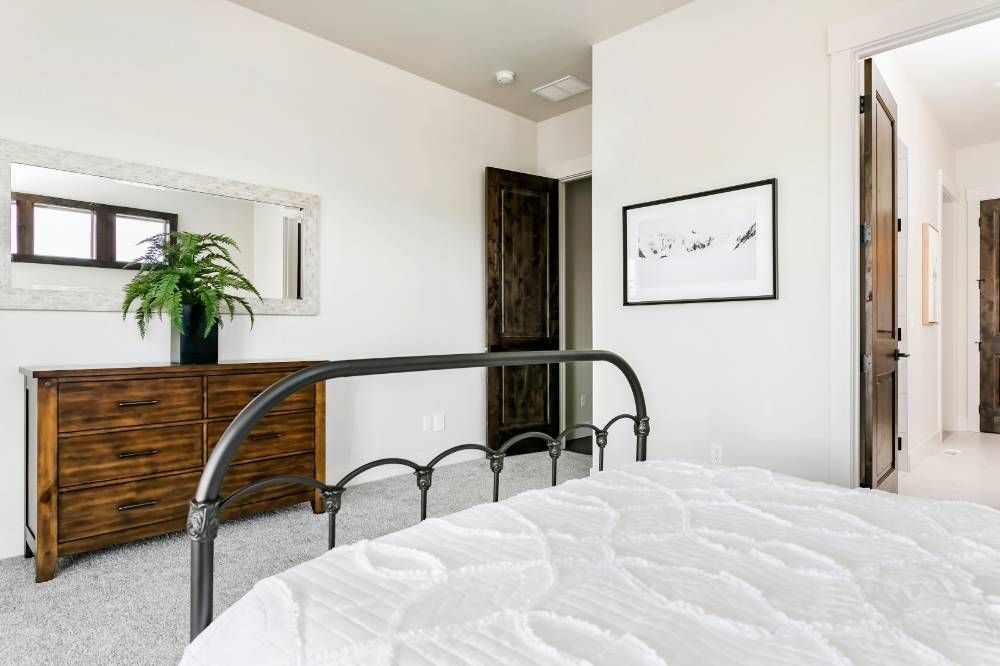 A bedroom with a bed , dresser , mirror and a picture on the wall.
