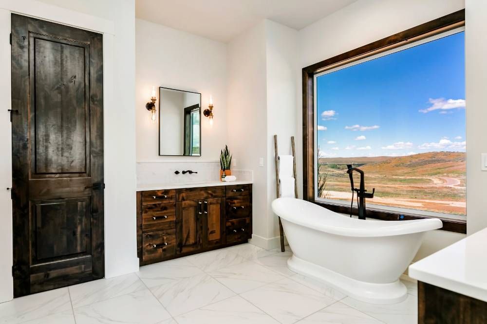 A bathroom with a tub , sink , mirror and window.