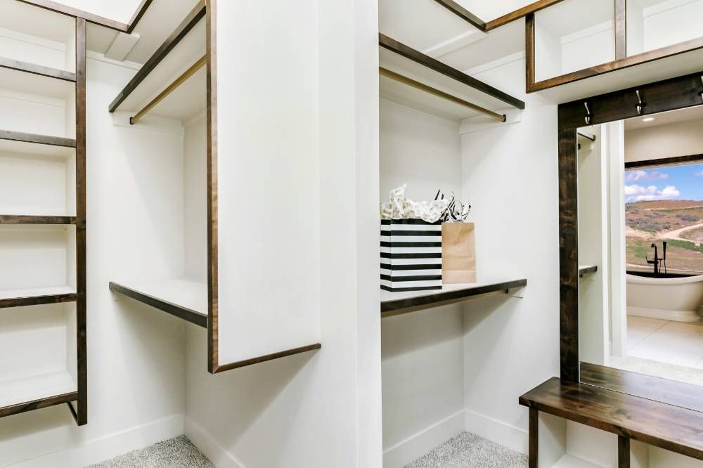 A walk in closet with lots of shelves and a wooden bench.