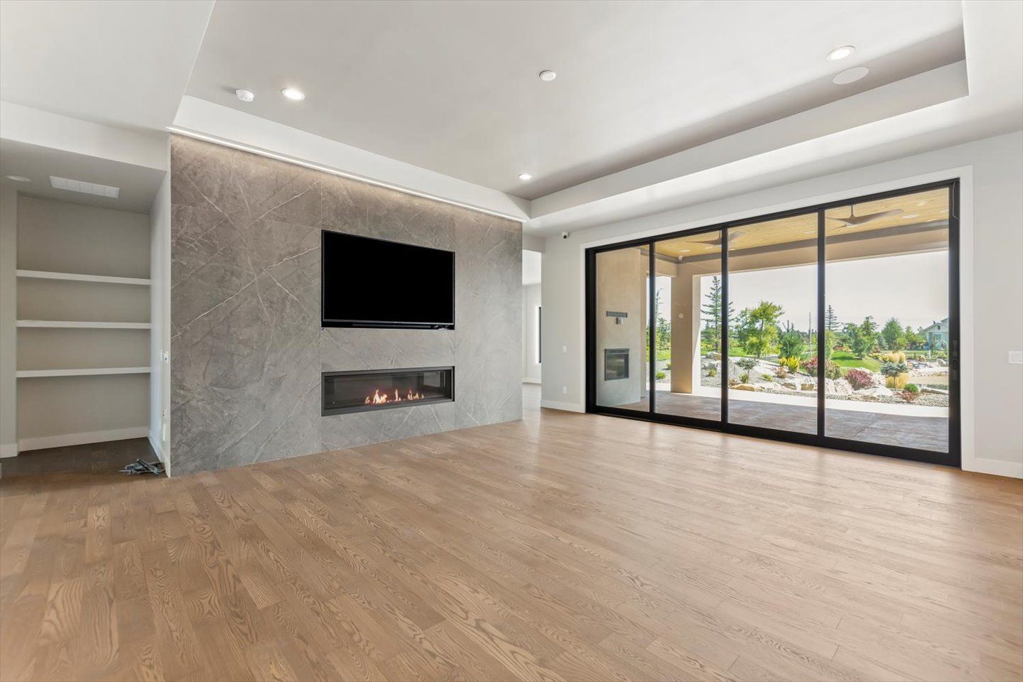 An empty living room with hardwood floors , a fireplace and a flat screen tv.