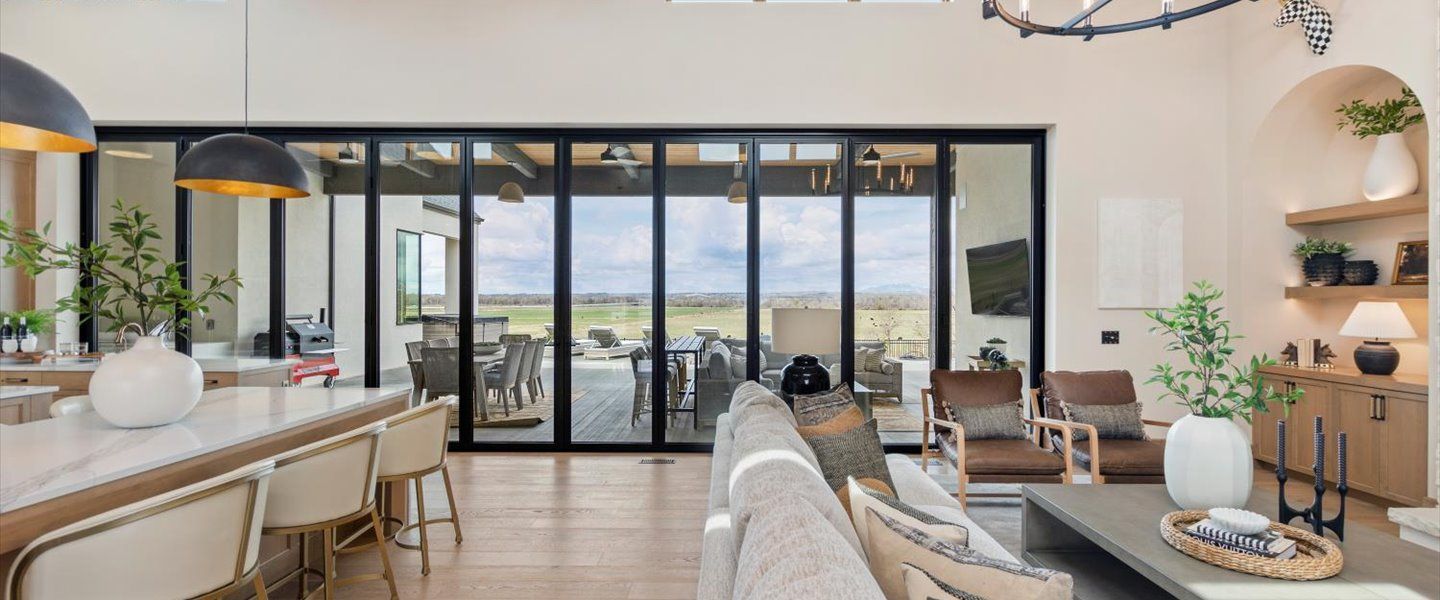 A living room with a lot of windows and a view of a field.