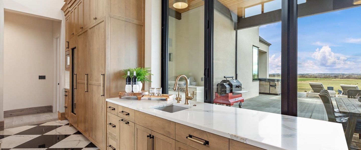 A kitchen with a sink , cabinets , and a large window.
