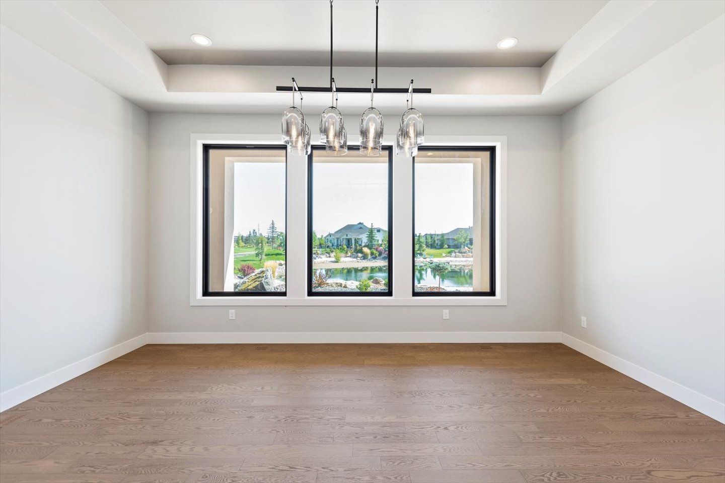 An empty room with three windows and a chandelier.