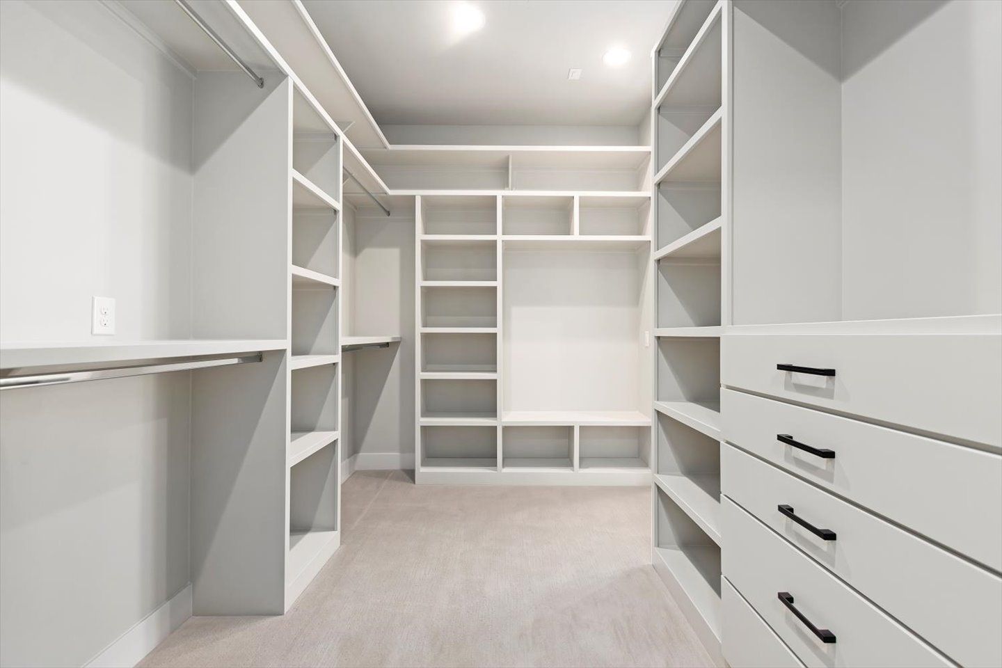 An empty walk in closet with lots of shelves and drawers.