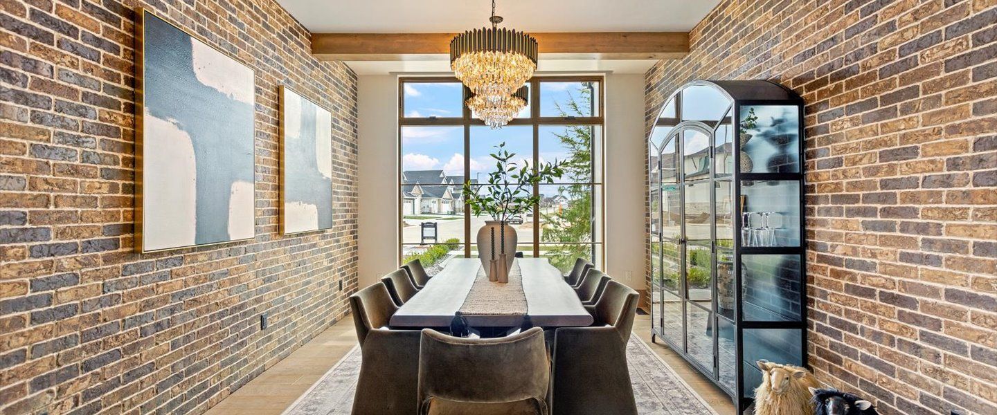 A dining room with a long table and chairs and a brick wall.