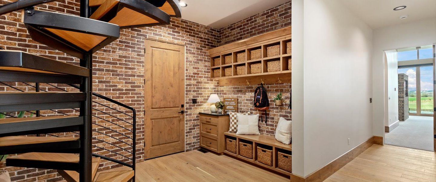 A hallway with a spiral staircase and a brick wall.