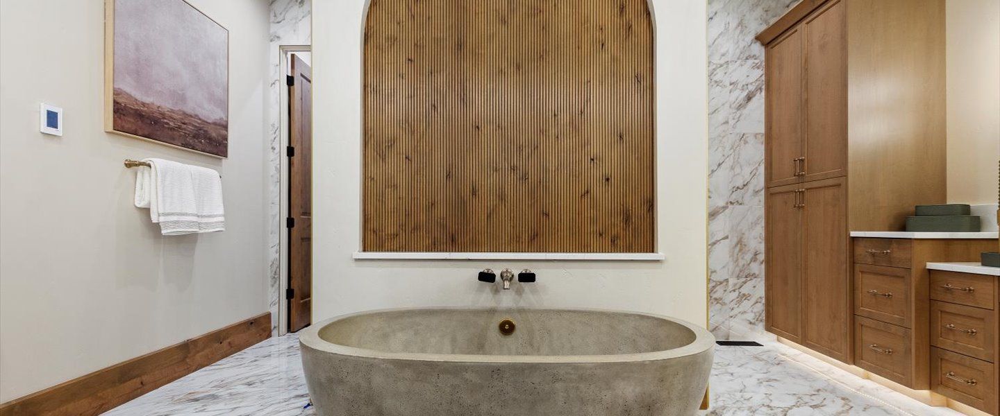A bathroom with a large stone tub and a wooden wall.