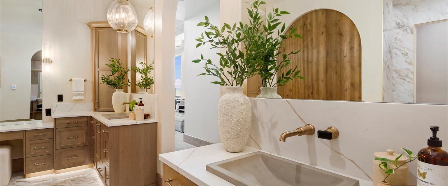 A bathroom with two sinks , a mirror and a vase of plants.