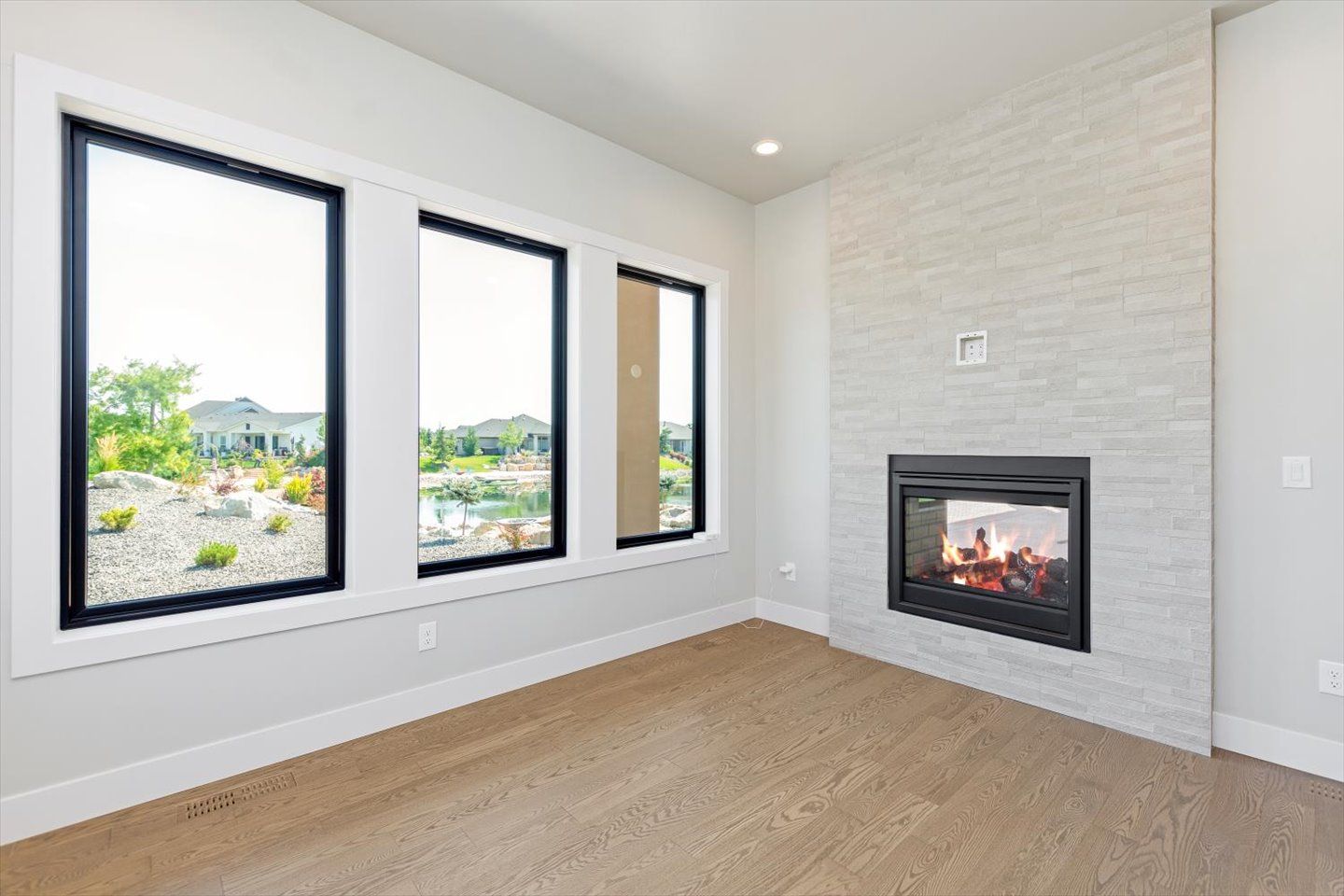 An empty living room with a fireplace and three windows.
