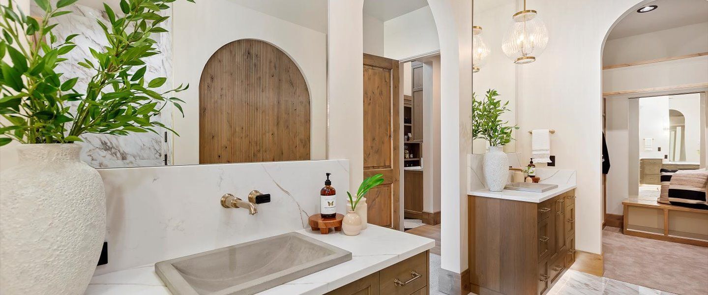 A bathroom with a sink , mirror and wooden cabinets.