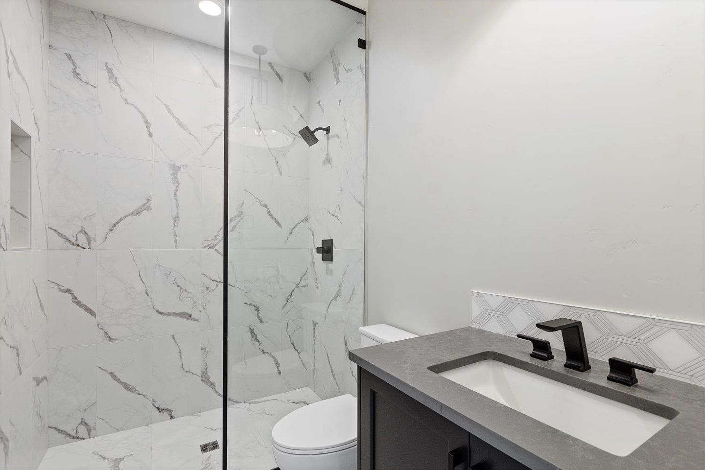 A bathroom with a toilet , sink and walk in shower.