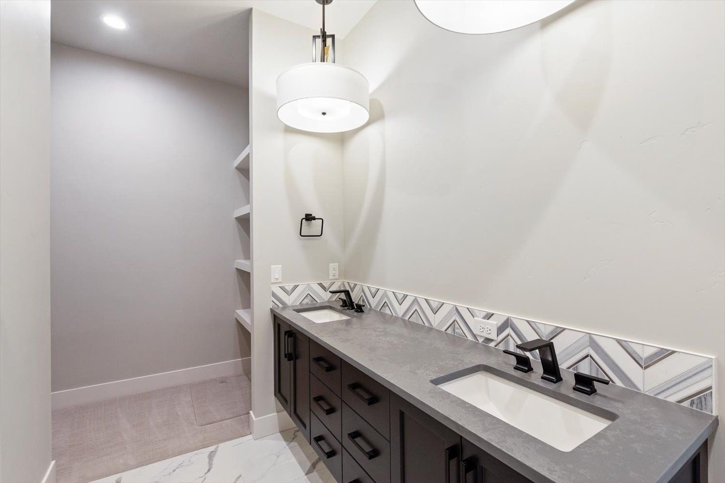 A bathroom with two sinks and a pendant light.
