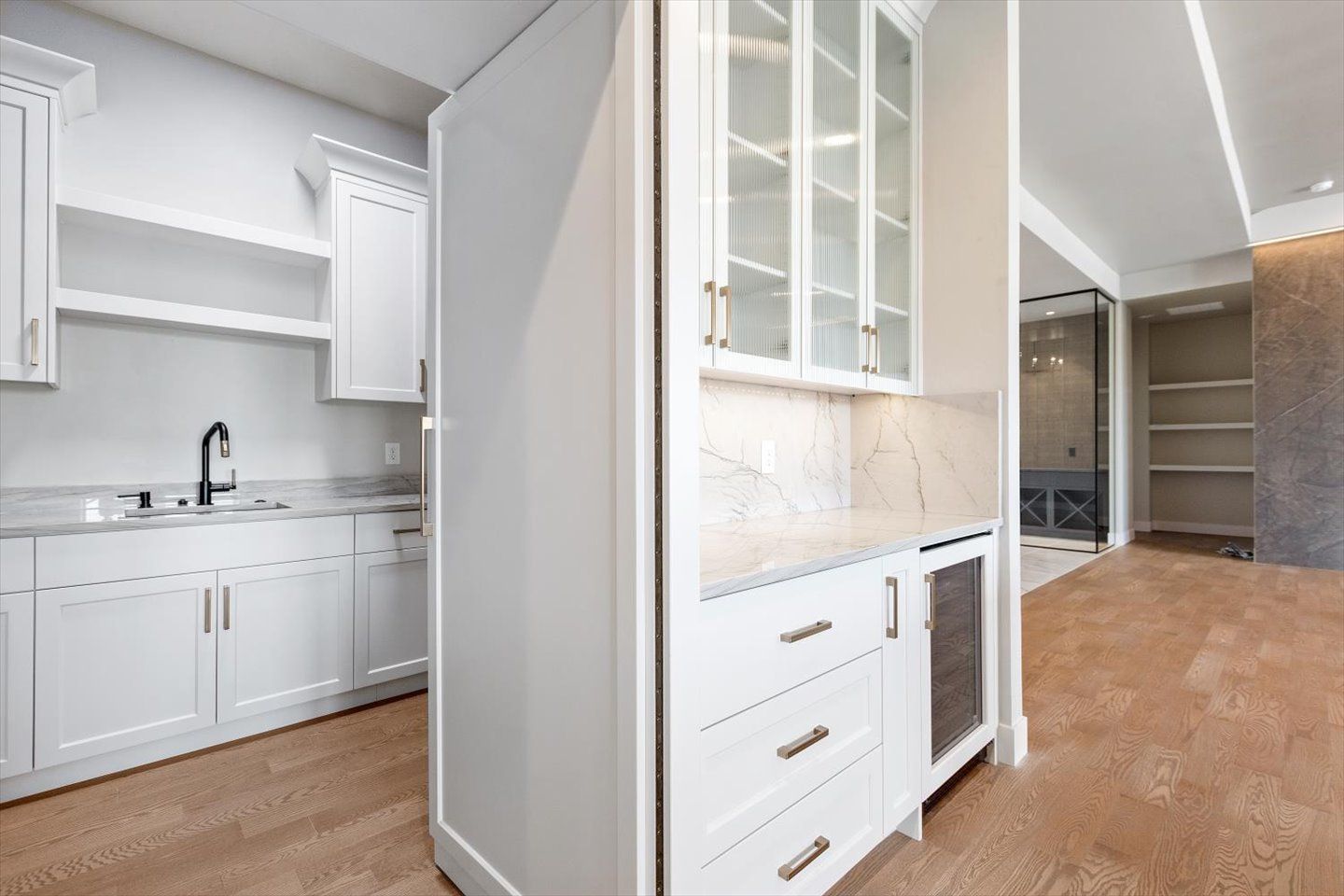 A kitchen with white cabinets , a sink , and a refrigerator.