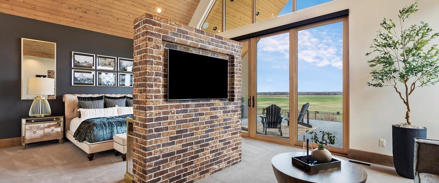 A bedroom with a brick wall and a flat screen tv on the wall.