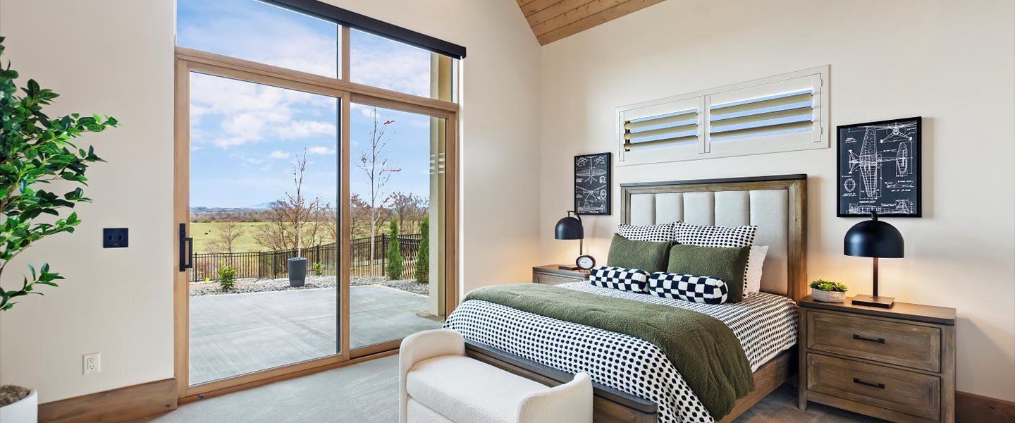 A bedroom with a bed , nightstand , bench and sliding glass doors.