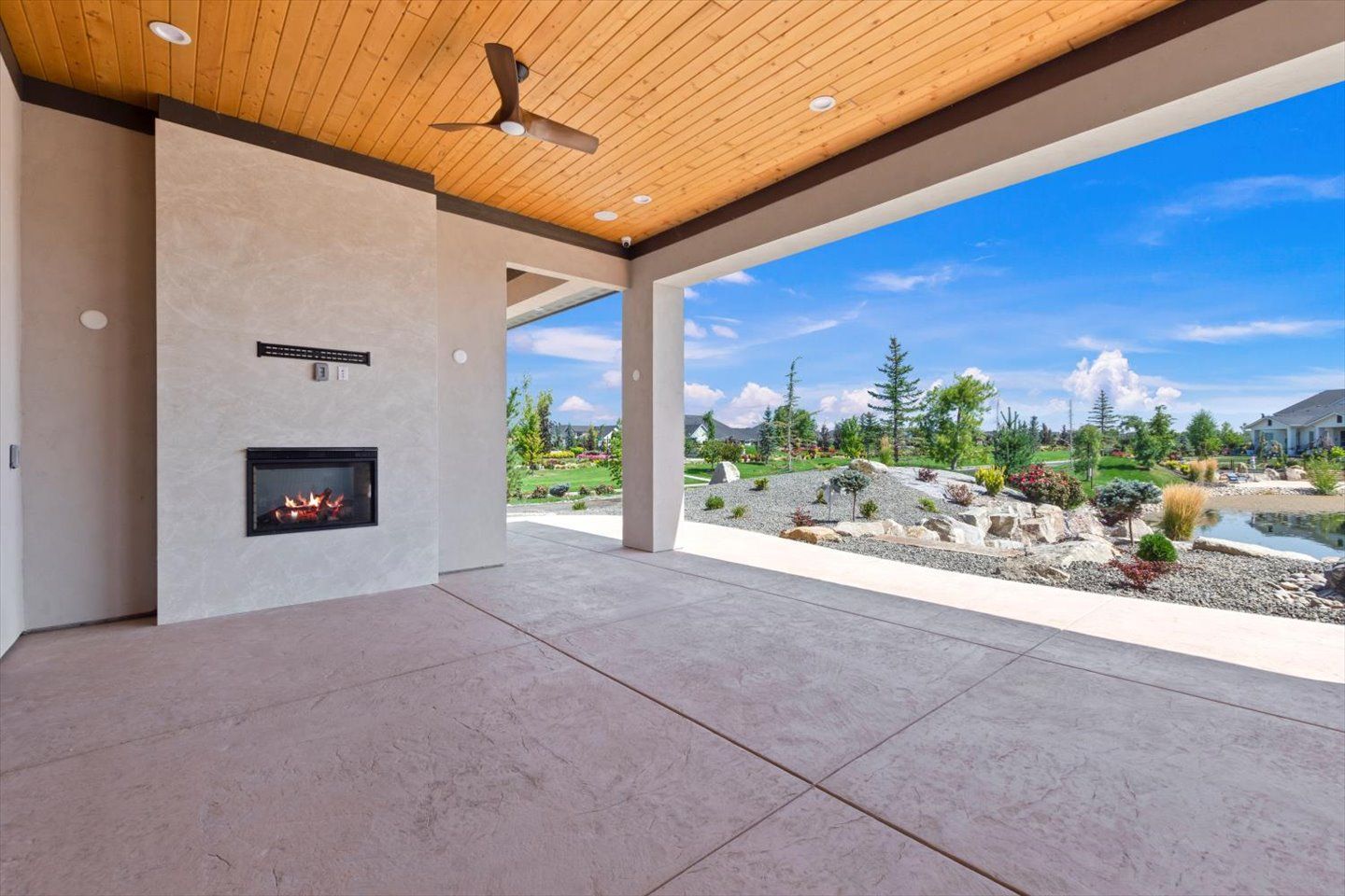 An empty patio with a fireplace and a ceiling fan.