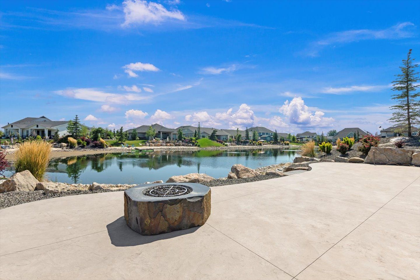 A fire pit is sitting on a concrete patio next to a lake.