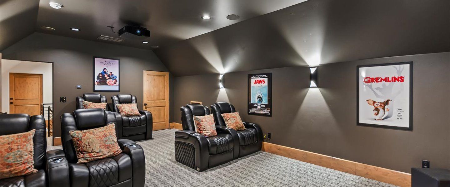 A home theater with a couch , chairs and a projector.
