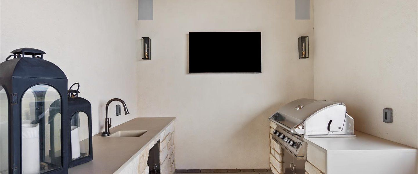 A kitchen with a grill and a flat screen tv on the wall.
