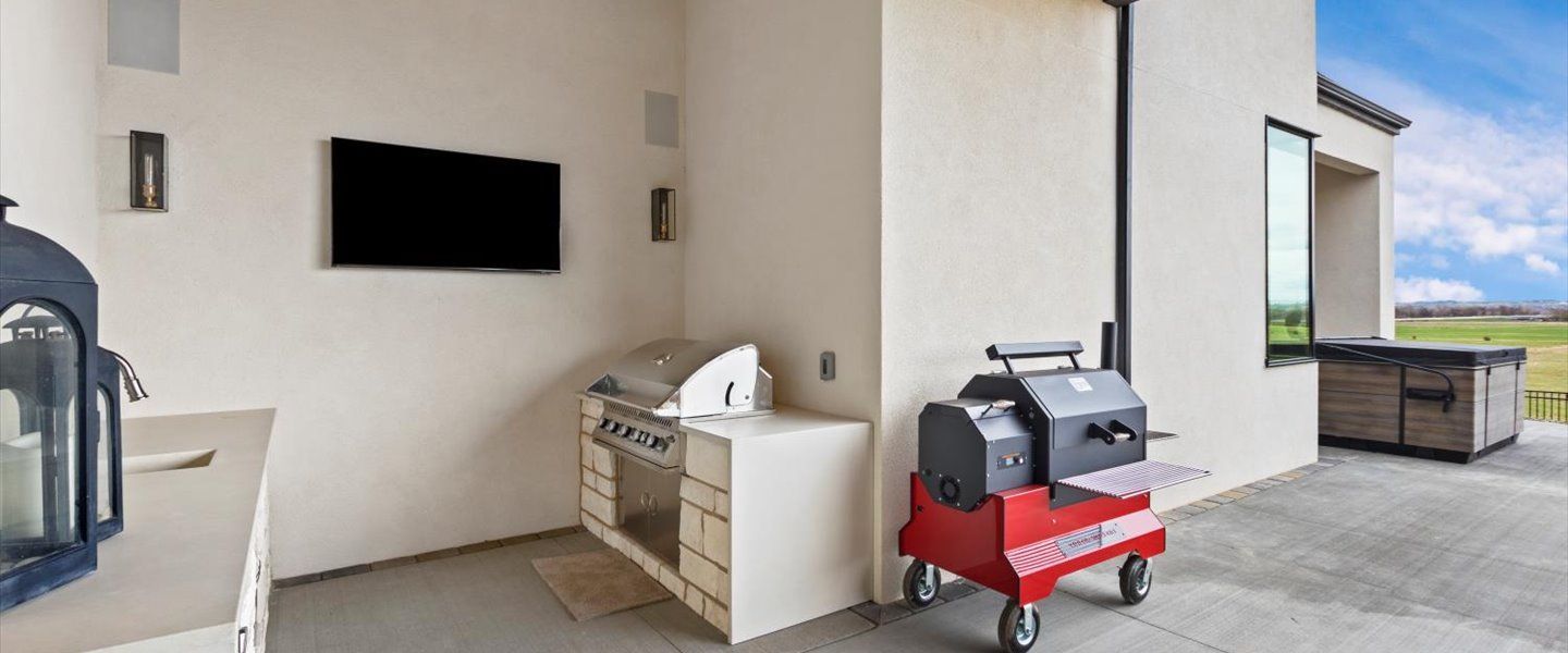 A kitchen with a grill and a television on the wall.