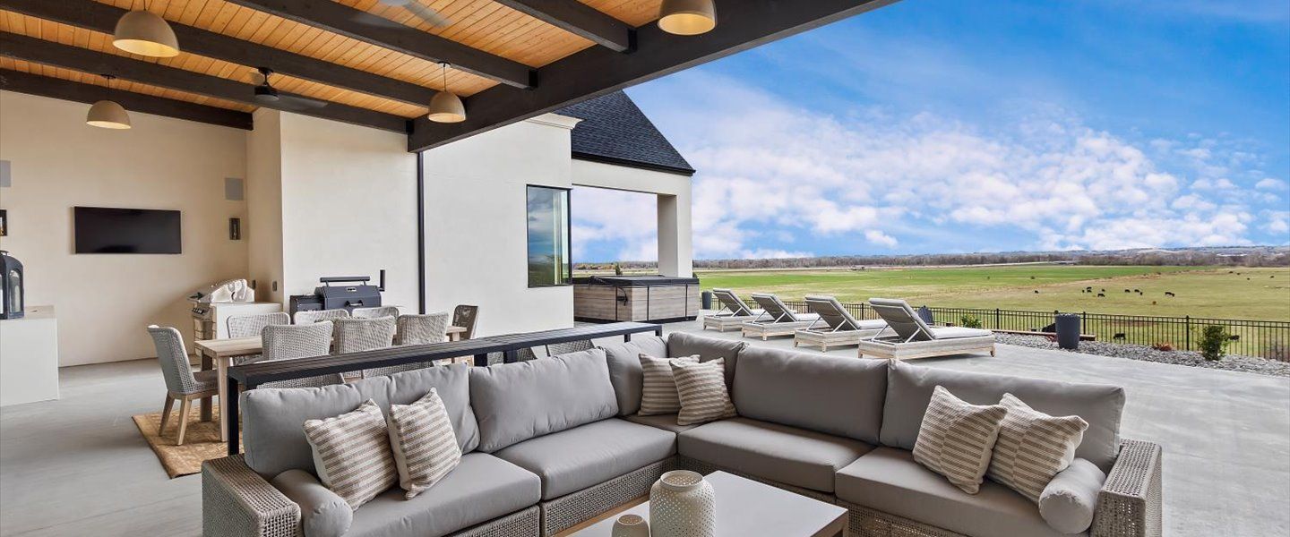 A living room with a couch and a table with a view of a field.