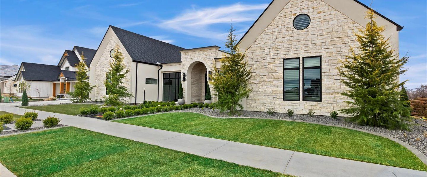 A large brick house with a lush green lawn and a sidewalk in front of it.