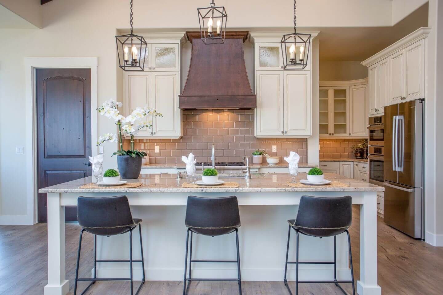 A kitchen with white cabinets , granite counter tops , stainless steel appliances and a large island.