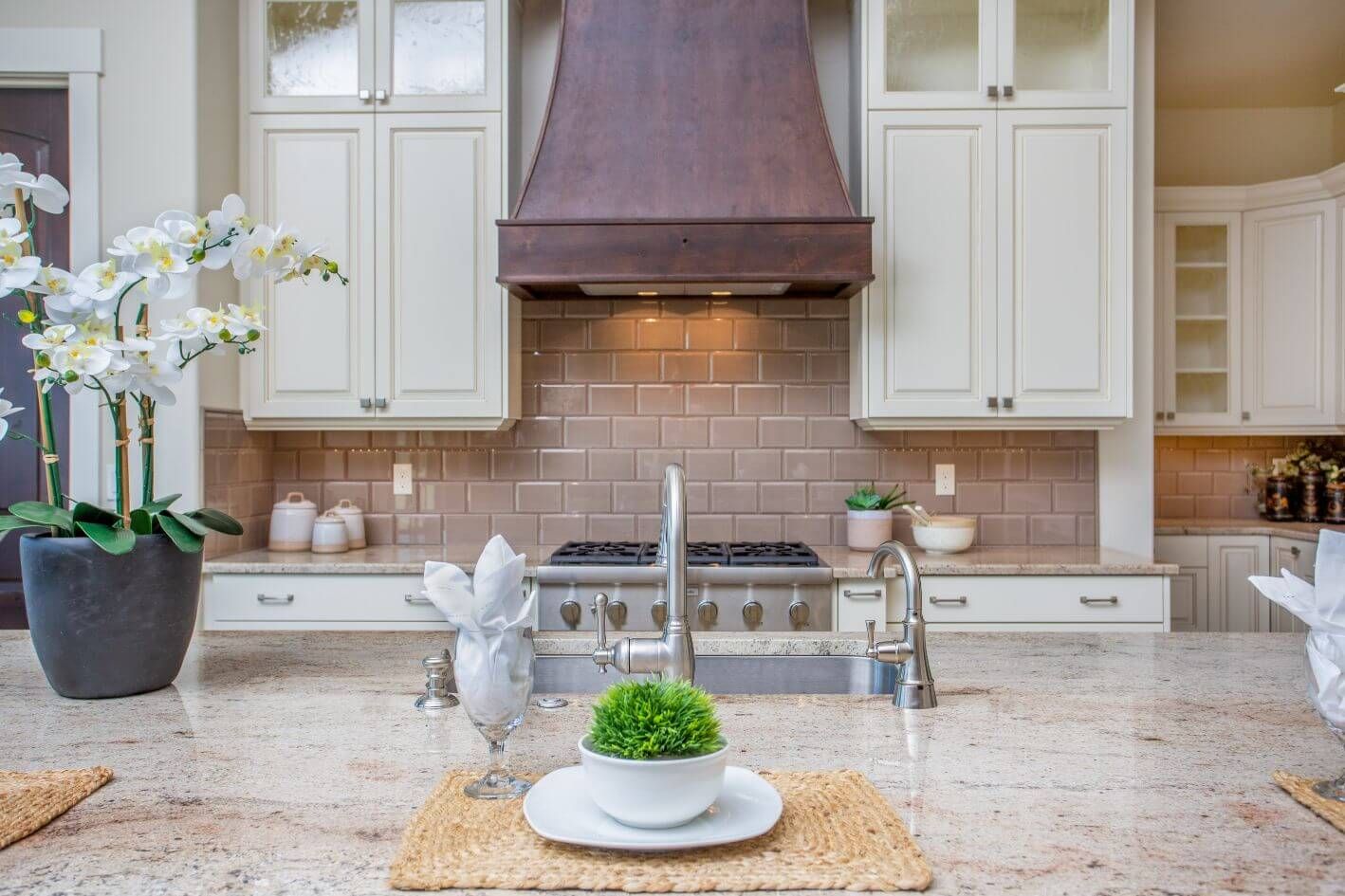 A kitchen with white cabinets , granite counter tops , a stove and a sink.