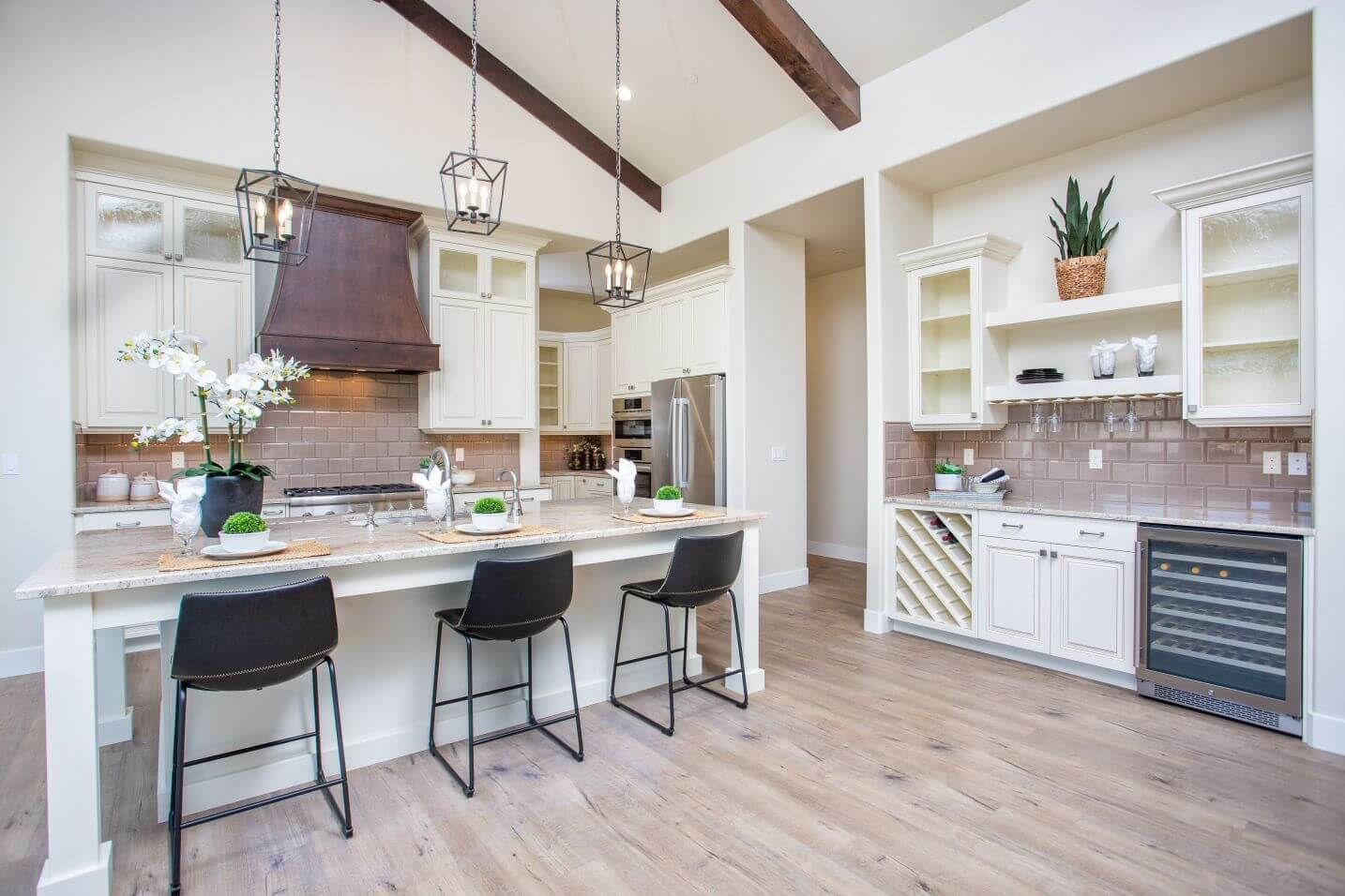 A kitchen with a large island and stools in it.